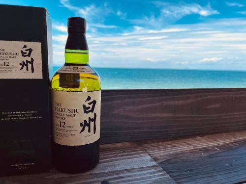 a bottle of wine sitting next to a window with the ocean at AWAJI OCEAN BASE west coast in Tsushi