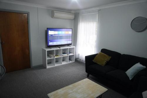 a living room with a couch and a flat screen tv at Chevy Cottage in Esperance