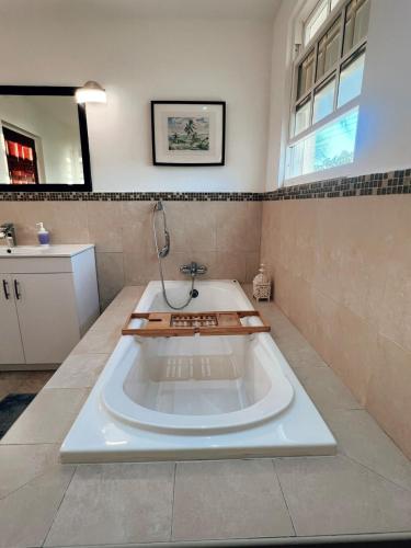 a large bath tub in a bathroom with a sink at Oistins Gem 2BR, 2BA Condo, Pool & Rooftop Patio, Walk to Miami Beach in Christ Church