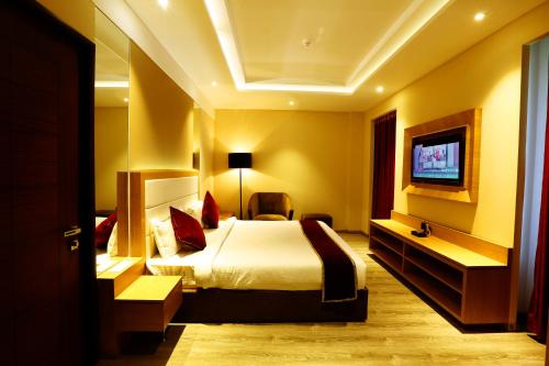 a hotel room with a bed and a tv at Park Blu in Sonīpat