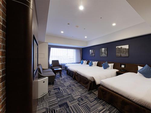a hotel room with three beds and a tv at The Park Front Hotel at Universal Studios Japan in Osaka