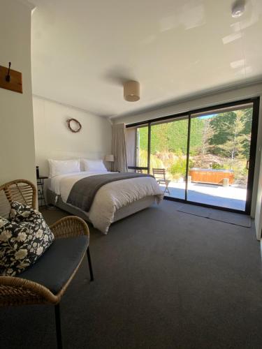 Un dormitorio con una cama y una ventana grande. en The Black House with Stunning Outdoor Bath, en Lake Tekapo