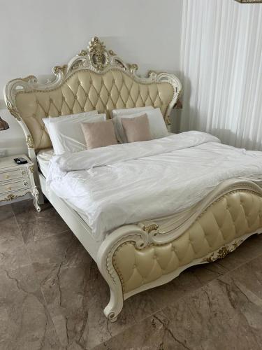 a white bed with a gold frame and white sheets at Coco villa & resort in Qiryat Ata