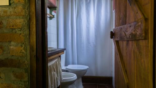 a bathroom with a toilet and a white shower curtain at Posada Hale Koa in La Paloma