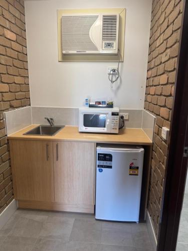 a small kitchen with a microwave and a sink at Albury Classic Motor Inn in Albury