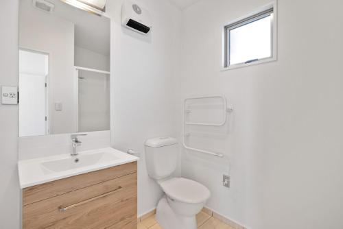 a white bathroom with a toilet and a sink at Chic City Apartment, Sleeps 7, Pool, Gym & 2 Parks in Christchurch
