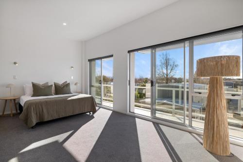 a bedroom with a bed and large glass windows at Chic City Apartment, Sleeps 7, Pool, Gym & 2 Parks in Christchurch
