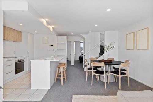 a kitchen and dining room with a table and chairs at Chic City Apartment, Sleeps 7, Pool, Gym & 2 Parks in Christchurch