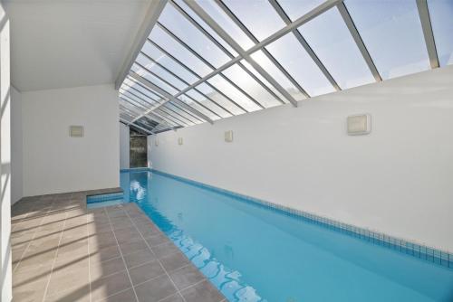 an indoor swimming pool with a skylight in a building at Chic City Apartment, Sleeps 7, Pool, Gym & 2 Parks in Christchurch