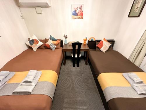 a room with two beds and a wooden table at nestay house tokyo shinjuku in Tokyo