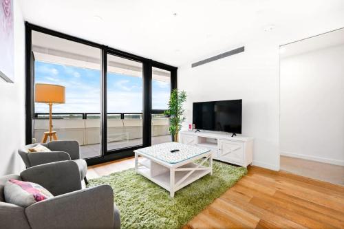 a living room with a couch and a tv at Galleria - Sleek & Sunlit Living in Glen Waverley in Glen Waverley