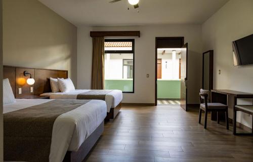 ein Hotelzimmer mit zwei Betten und einem Schreibtisch in der Unterkunft Aura Hotel in Uruapan del Progreso