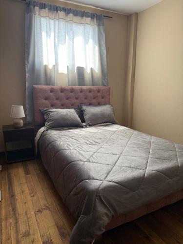 a bedroom with a large bed with a window at Encanto Colonial Apartamento Centro Histórico in Cuenca