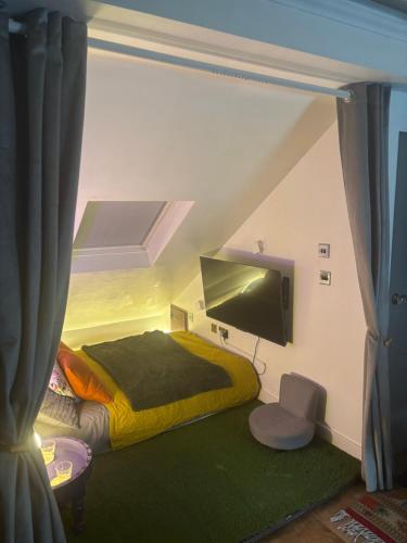 Una pequeña habitación con una cama y un televisor. en The Snug in a Quaint English Mews House, en Londres