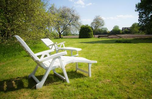 two white lawn chairs sitting in the grass at Adelheidshof in Magelsen