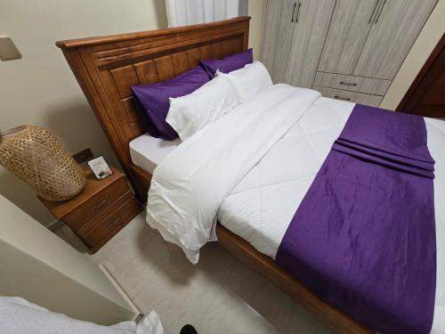 a large bed with purple and white sheets and pillows at Vibrant City Haven in the Heart of Kampala in Kampala