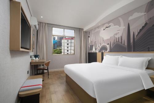 a bedroom with a large white bed and a desk at Thank You Hotel Sanya Bay Coconut Dream Corridor Branch in Sanya