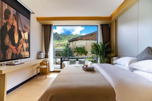 une chambre avec une grande fenêtre et un grand lit dans l'établissement Xuejian Homestay, à Shangri-La