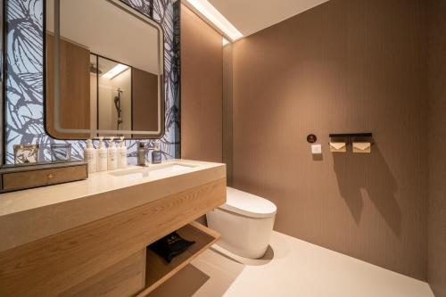 een badkamer met een wastafel, een toilet en een spiegel bij Mehood Lestie in Jinghong