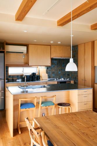 a kitchen with wooden cabinets and a table with chairs at Kiyose Garden Stay - 最大10名でゆったり過ごせる宿 in Matsuyama