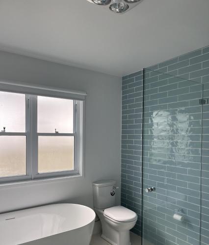 a bathroom with a tub and a toilet and a window at Bluebell Huskisson in Huskisson
