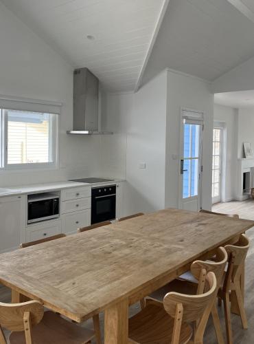 a large kitchen with a wooden table and chairs at Bluebell Huskisson in Huskisson