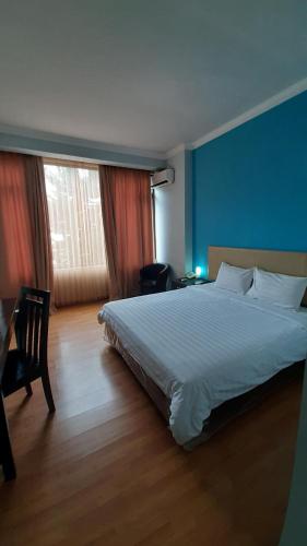 a bedroom with a white bed and a blue wall at Hotel Prasasti Pacitan in Pacitan