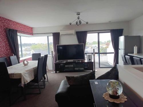 a living room with a television and a table with chairs at Spacious City Apartment With Amazing Views in Christchurch