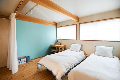 two beds in a room with two windows at Kiyose Garden Stay - 最大10名でゆったり過ごせる宿 in Matsuyama
