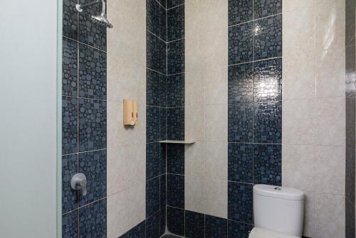 a bathroom with a toilet and a shower with black tiles at RedDoorz Plus @ Jalan Pemuda Jakarta in Jakarta