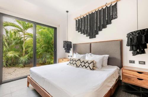 a bedroom with a large bed and a large window at Villa Paradise Tulum Veleta 4BR private pool & jacuzzi in Tulum