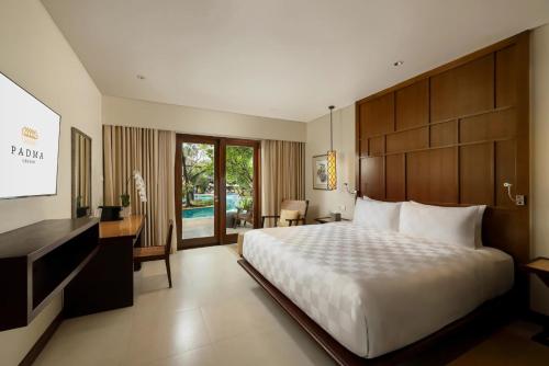 ein Hotelzimmer mit einem Bett, einem Schreibtisch und einem Fernseher in der Unterkunft Padma Resort Legian in Legian
