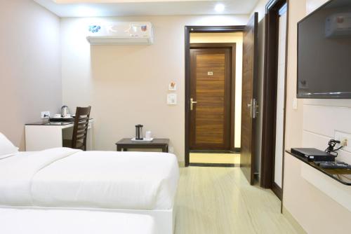 a hotel room with a white bed and a door at Hotel Tara Palace Redfort in New Delhi