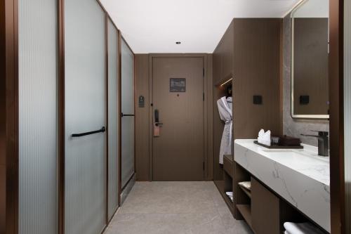 a bathroom with a sink and a person standing in the doorway at Mehood Lestie Hotel, Nanjing Xinjiekou Subway Station in Nanjing