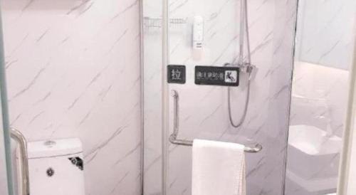 a bathroom with a shower with a toilet and a towel at 7 Days Premium Xianning Wenquan Shopping Center in Xianning