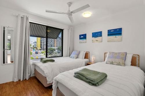two beds in a room with a window at Levuka Unit 12 14 Moreton Pde in Caloundra