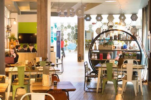 a restaurant with wooden tables and chairs and people in the background at Novotel Manchester Centre in Manchester