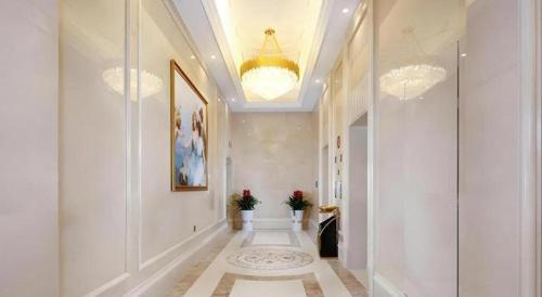 a hallway with white walls and a chandelier at Vienna Hotel Baoshan Yongchang Road in Baoshan