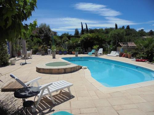 a swimming pool with a bench and chairs next to it at Les ailes d'un reve in Vidauban