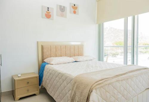 a white bedroom with a bed and a window at Apto Premium con vista al Mar en Pozos Colorados in Playa Bello Horizonte
