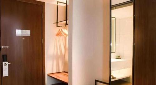 La salle de bains est pourvue d'une porte, d'un lavabo et d'un miroir. dans l'établissement Borrman Hotel Baise High-speed Railway Station Hengning Plaza, à Baise