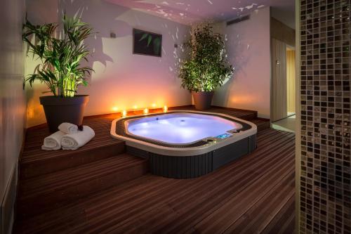 a hot tub in a room with plants and lights at Hôtel Le Rive Droite & SPA in Lourdes
