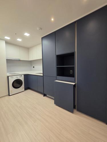 a kitchen with black cabinets and a washer and dryer at Central H apartment Grande in Busan