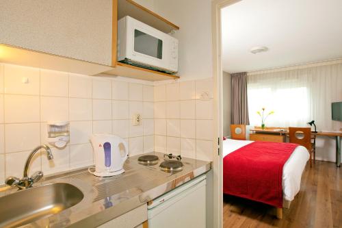 a kitchen with a sink and a room with a bed at Séjours & Affaires Poitiers Lamartine in Poitiers