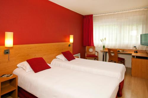 ポワティエにあるセジュール & アフェール ポワティエ マルティーヌのベッド2台とデスクが備わるホテルルームです。