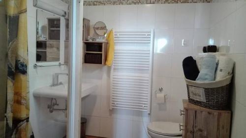Baño blanco con lavabo y aseo en Gartenwohnung auf der Sommeralm en Sankt Kathrein am Offenegg