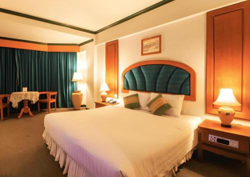 a hotel room with a large bed and a table at Thepnakorn Hotel in Buriram