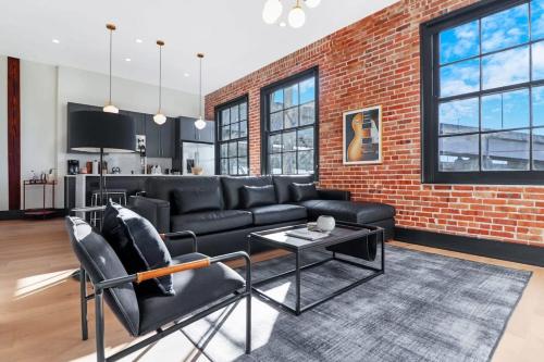a living room with a black couch and a brick wall at Roami at Brassline in New Orleans