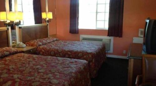 a hotel room with two beds and a television at Coast Motel in Los Angeles