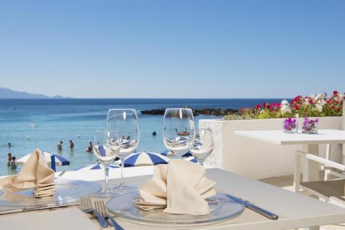 a table with wine glasses and a view of the ocean at Hotel Dei Pini in Alghero